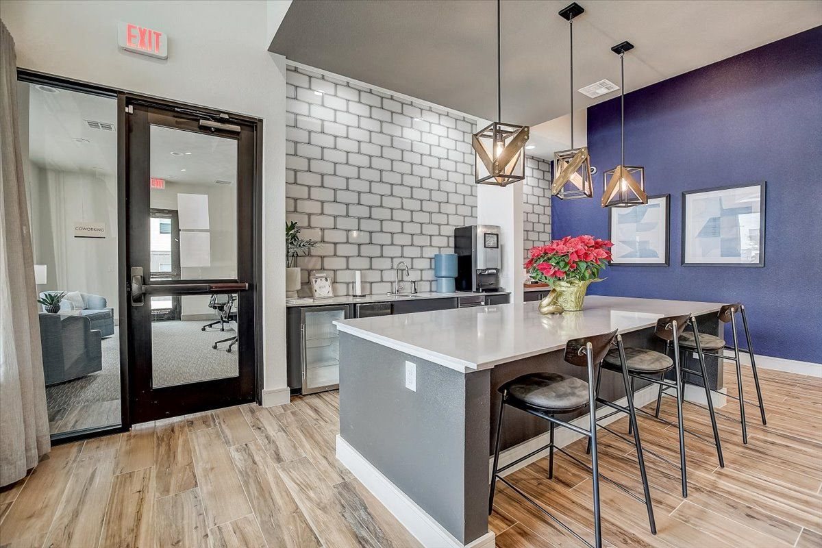 Clubhouse kitchen island with barstool seating, modern pendant lights, and nearby sink and prep counter.